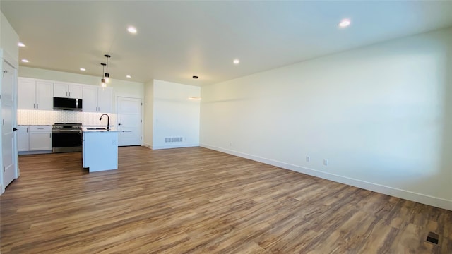 kitchen with visible vents, backsplash, appliances with stainless steel finishes, open floor plan, and a sink