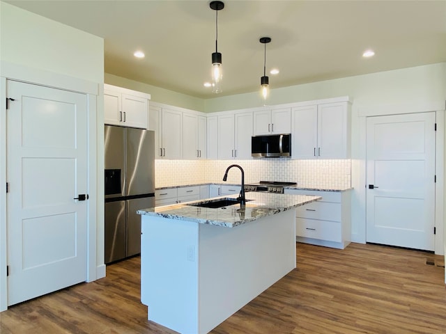 kitchen featuring dark wood-style flooring, a sink, appliances with stainless steel finishes, backsplash, and light stone countertops