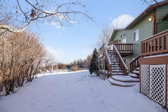 yard layered in snow featuring stairway and a wooden deck