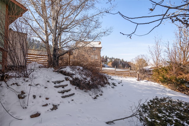 yard covered in snow with a garage and fence