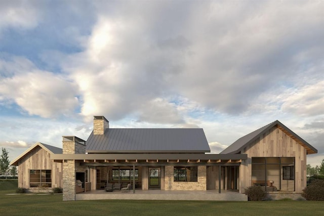 rear view of house featuring metal roof, a chimney, a patio area, and a lawn