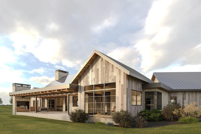 back of property featuring a yard, a chimney, metal roof, and a patio