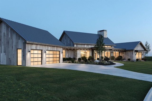 view of front facade featuring concrete driveway, metal roof, an attached garage, a standing seam roof, and a front lawn