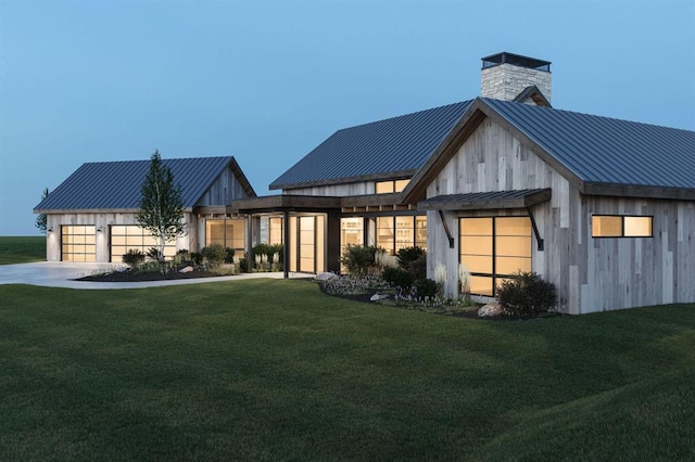 view of front of house with metal roof, a yard, a standing seam roof, and a chimney