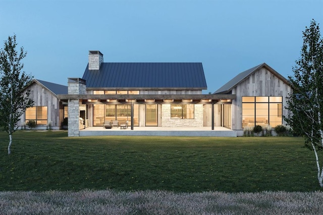 back of house featuring a patio, a chimney, a lawn, metal roof, and stone siding