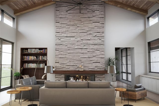 living area featuring wooden ceiling, high vaulted ceiling, beam ceiling, and a stone fireplace