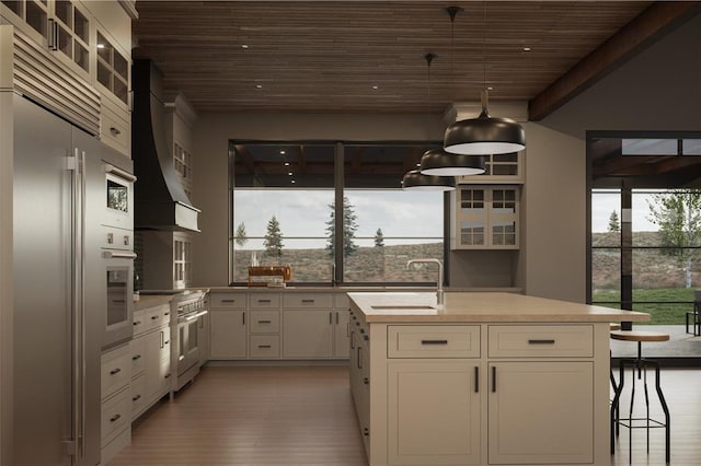 kitchen with premium appliances, custom exhaust hood, light countertops, glass insert cabinets, and white cabinets