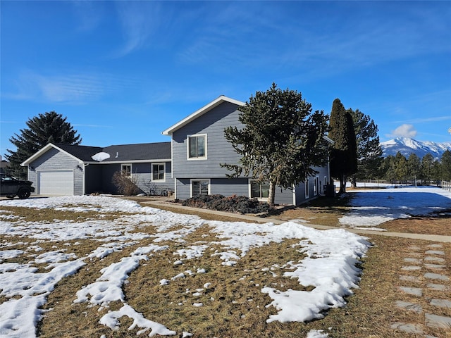 snow covered property featuring an attached garage and a mountain view