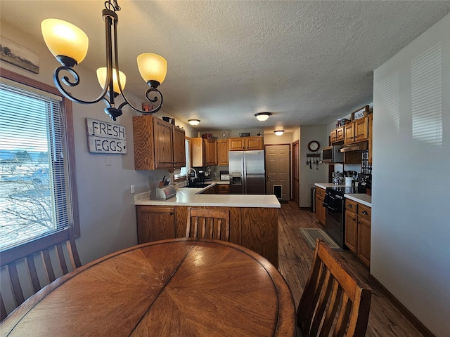 kitchen featuring a peninsula, appliances with stainless steel finishes, a sink, and light countertops