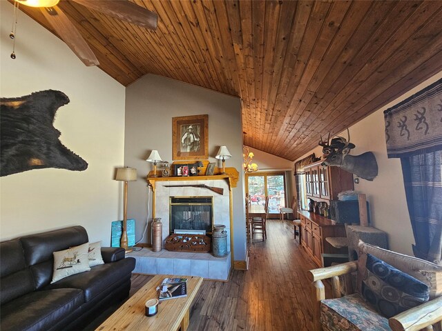 living area featuring vaulted ceiling, a tiled fireplace, wood finished floors, and wooden ceiling