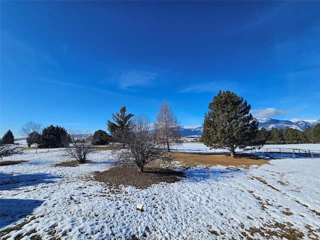 snowy yard featuring fence and a mountain view