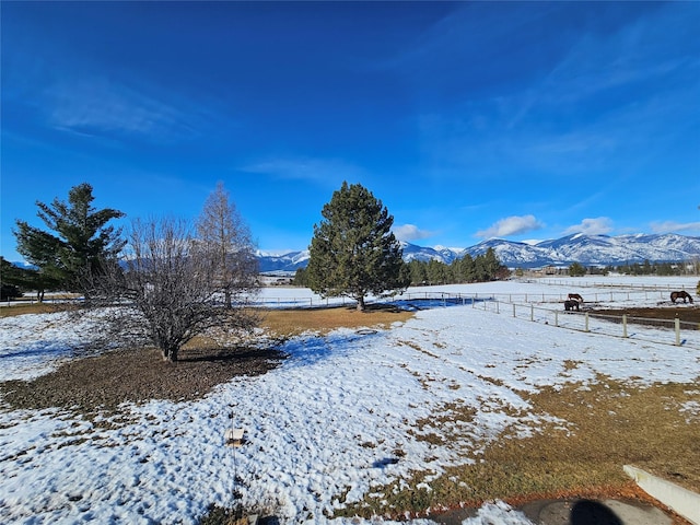 yard layered in snow with fence and a mountain view