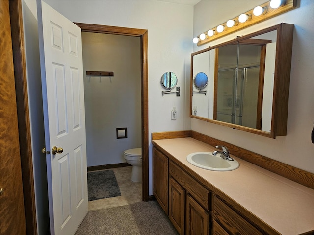 bathroom featuring toilet, a shower with shower door, baseboards, and vanity