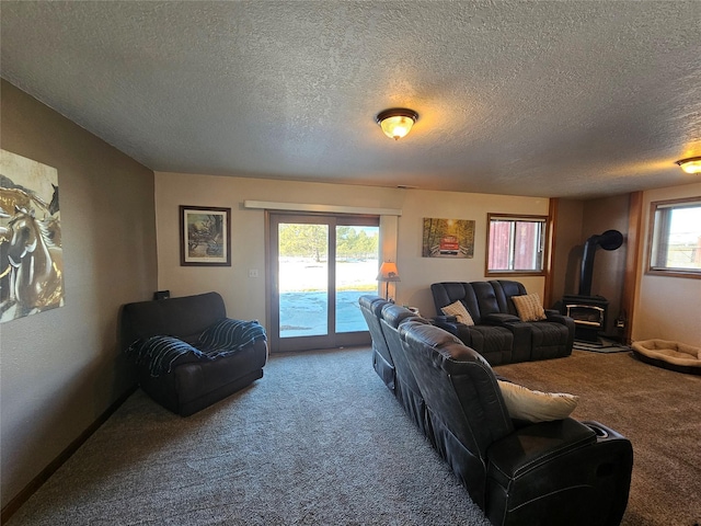 living room featuring carpet, a wood stove, a textured ceiling, and baseboards