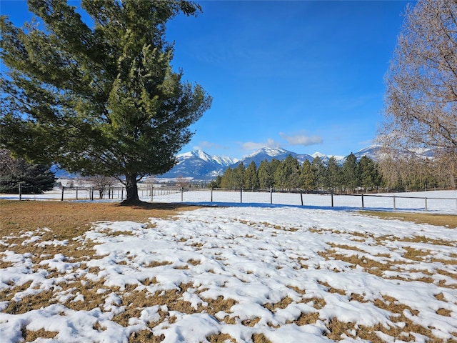 yard covered in snow featuring fence and a mountain view