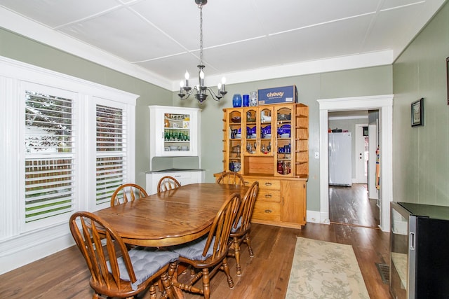 dining room featuring an inviting chandelier, wine cooler, and dark wood-type flooring