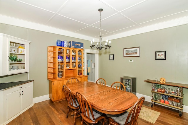 dining space featuring baseboards, dark wood finished floors, and a notable chandelier