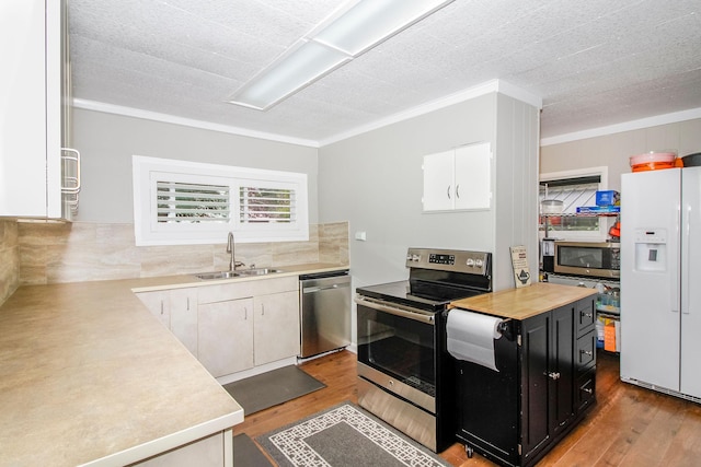 kitchen with appliances with stainless steel finishes, light countertops, a sink, and dark cabinetry