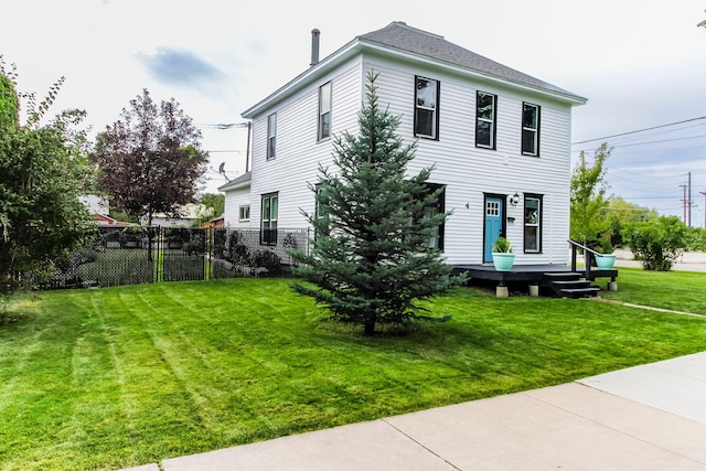 rear view of property with a wooden deck, fence, and a lawn