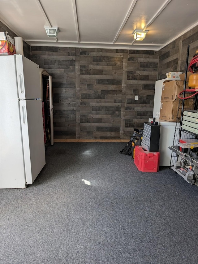 garage with freestanding refrigerator and wood walls