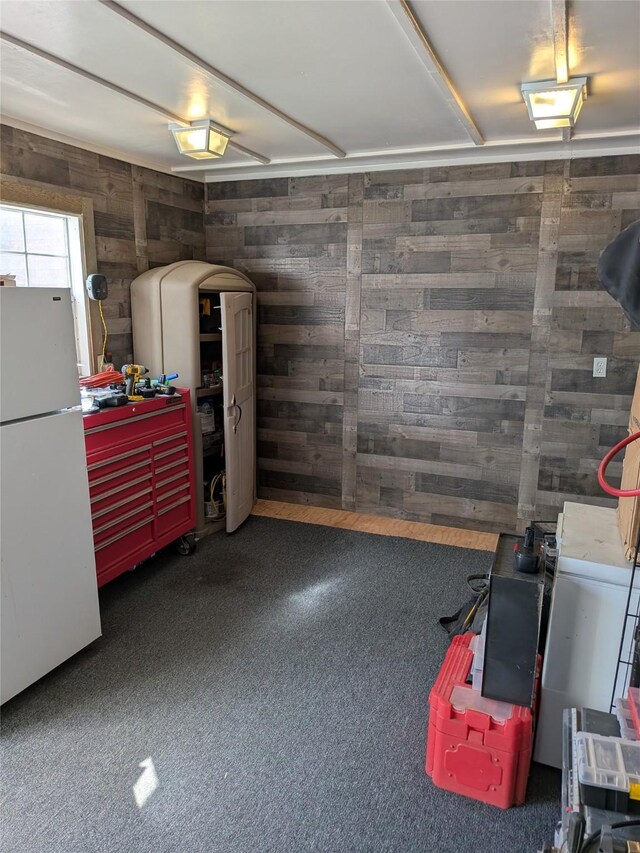 garage with freestanding refrigerator and wooden walls