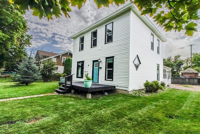 rear view of property with a yard, a deck, and fence