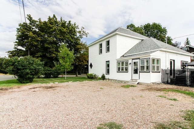 exterior space with entry steps, a shingled roof, and fence