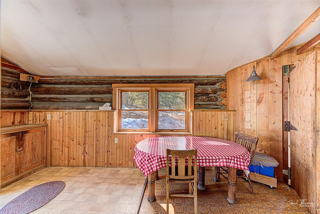 dining space with lofted ceiling, wood walls, and log walls