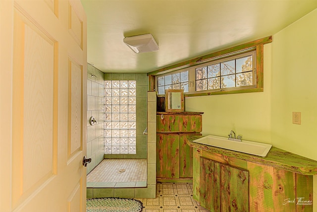 full bathroom with a sink, tiled shower, and tile patterned floors