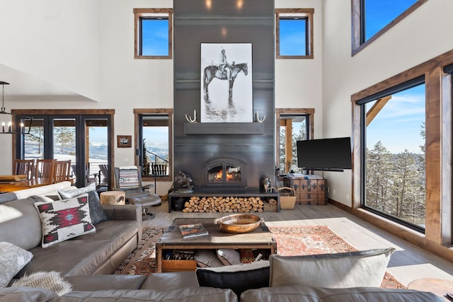 living area featuring a high ceiling, wood finished floors, a chandelier, and a large fireplace