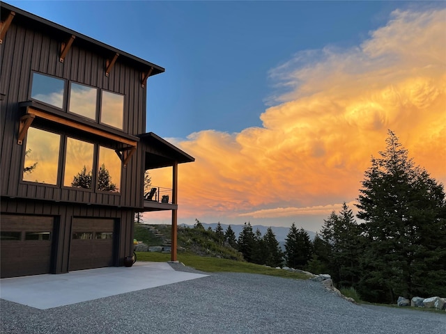 75 Meadows Dr, Whitefish, MT 59937 - property exterior at dusk with board and batten siding, a balcony, an attached garage, and driveway