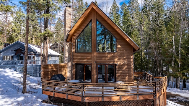 snow covered house with a chimney and a deck