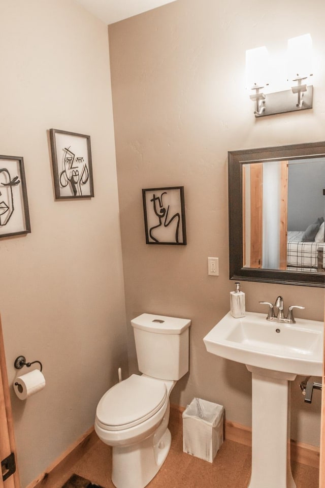 bathroom featuring toilet, baseboards, and a sink