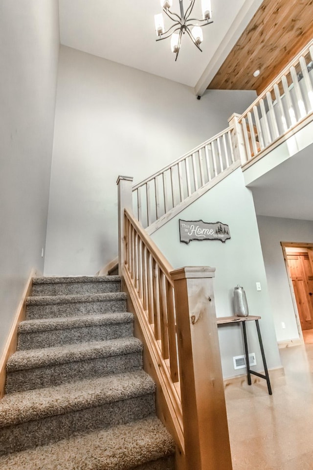 stairway with baseboards, visible vents, beamed ceiling, a high ceiling, and a chandelier