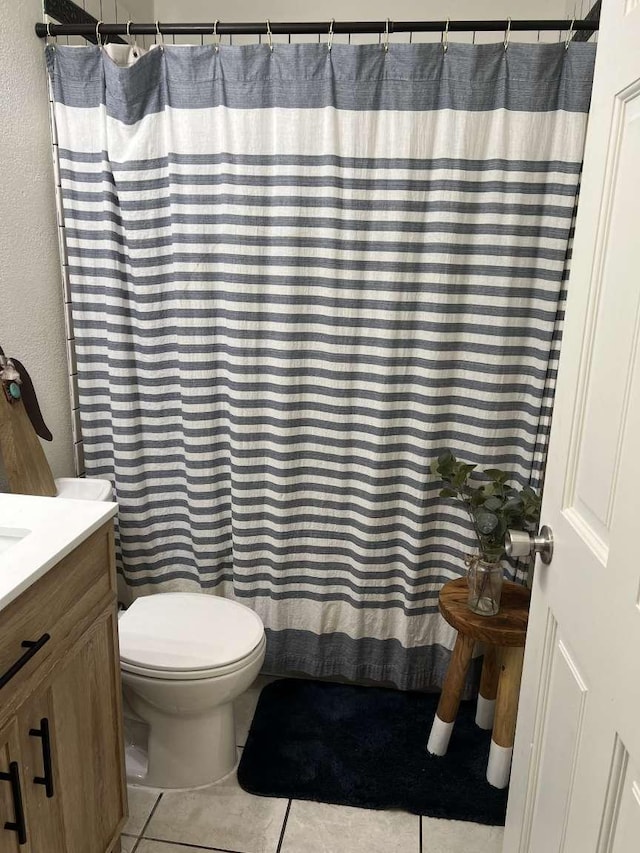 bathroom with toilet, curtained shower, vanity, and tile patterned floors