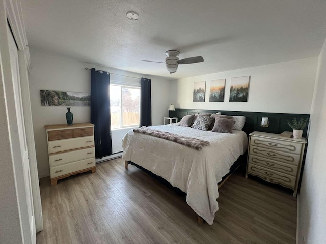 bedroom with a textured ceiling, a ceiling fan, and wood finished floors