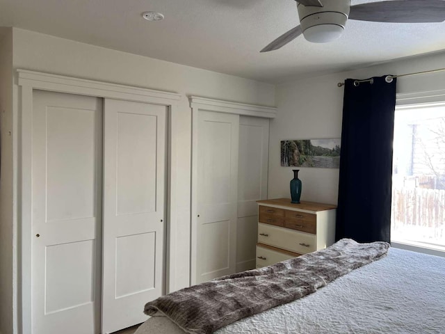 bedroom featuring ceiling fan, a textured ceiling, and two closets