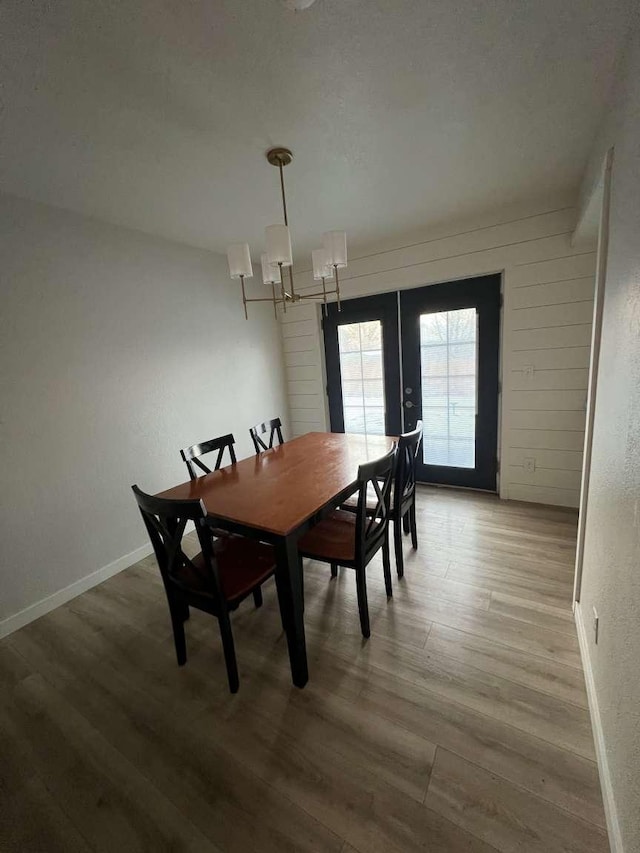 dining room with french doors, a notable chandelier, baseboards, and wood finished floors