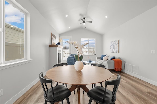 dining space with lofted ceiling, light wood-style flooring, visible vents, and baseboards