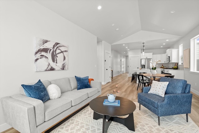 living area with recessed lighting, vaulted ceiling, light wood-style flooring, and baseboards