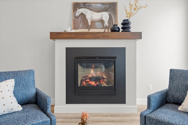 sitting room featuring baseboards, wood finished floors, and a glass covered fireplace