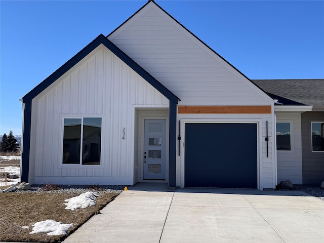 view of front facade with board and batten siding, a garage, driveway, and a shingled roof