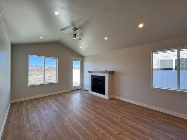 unfurnished living room with baseboards, a ceiling fan, lofted ceiling, wood finished floors, and a fireplace