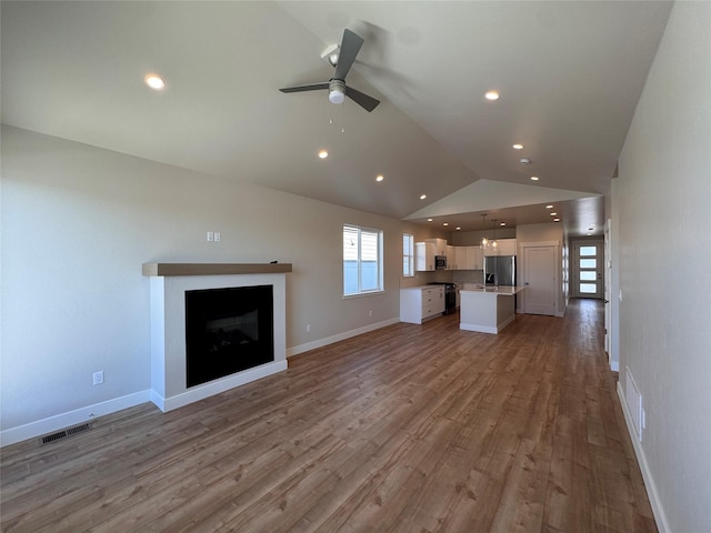 unfurnished living room featuring a fireplace, lofted ceiling, visible vents, light wood-style flooring, and baseboards