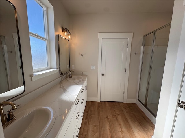 bathroom featuring wood finished floors, a stall shower, and a sink