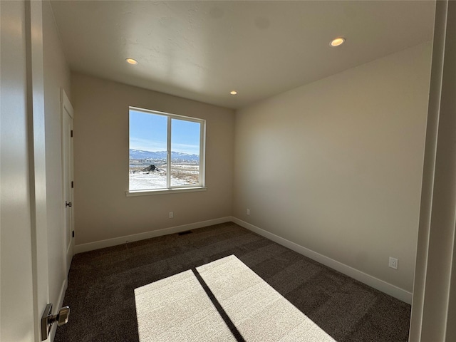 empty room featuring dark colored carpet, recessed lighting, and baseboards