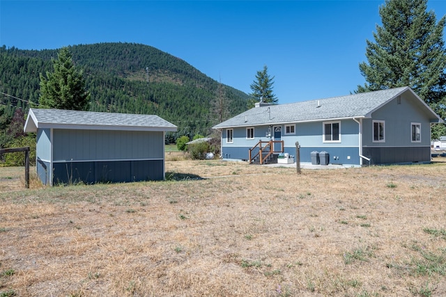 rear view of house featuring a wooded view and a mountain view