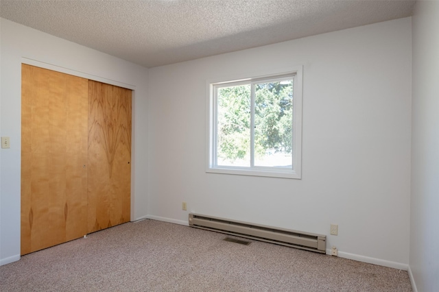 unfurnished bedroom featuring baseboards, a textured ceiling, carpet floors, a baseboard heating unit, and a closet