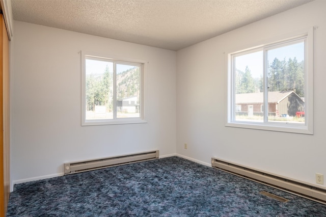 carpeted empty room with a textured ceiling, baseboard heating, and baseboards