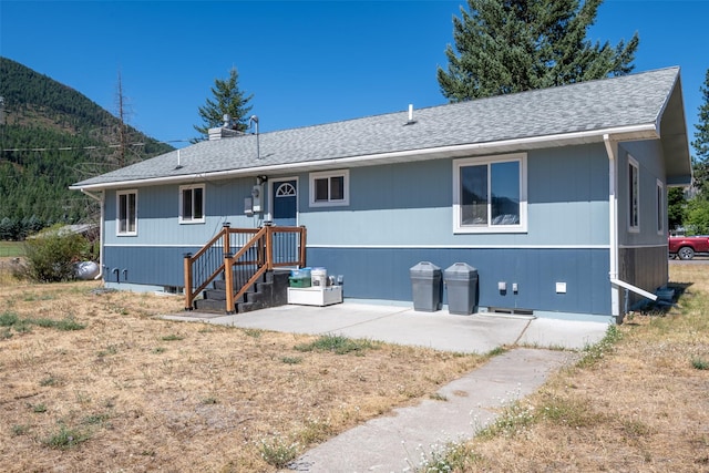 rear view of house with crawl space, a shingled roof, and a patio